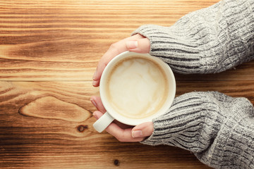 the woman is holding a cup of coffee on a wooden table