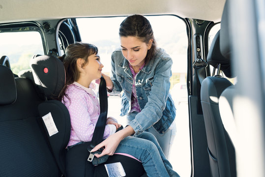 Woman helping her daughter to fasten seatbelts