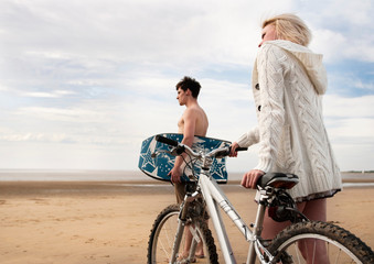 Couple on beach with bike & boogie board