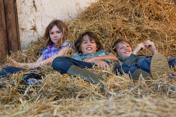 Three kids resting in hay © Image Source RF