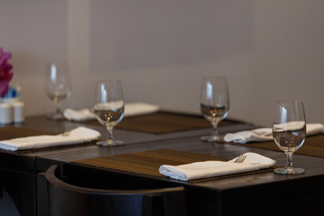 Dining table with spoon, knife and glass, with napkin and dish plate on the dining table.