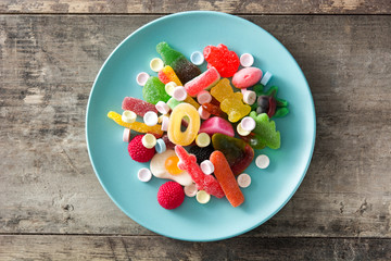 Colorful childs sweets and treats in plate on wooden table. Top view