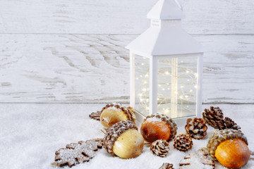 Christmas Lantern On Snow with acorns and oak leaves. Christmas scene.