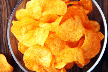 Crispy potato chips. Paprika chips on wooden background.