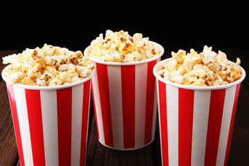 Paper cup in red and white with popcorn on wooden background
