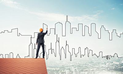 Man architect draw silhouette of modern city on blue sky. Mixed 