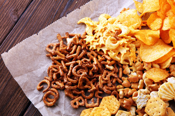 Obraz na płótnie Canvas Salty snacks. Pretzels, chips, crackers on brown wooden backgroun d