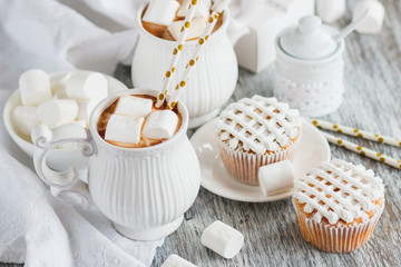 Cups with cacao and marshmallow, cupcakes and different decorations