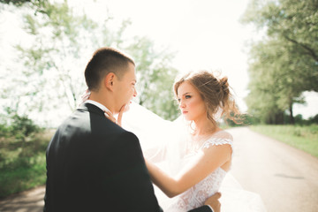 Naklejka premium Stylish couple of happy newlyweds walking in the park on their wedding day with bouquet