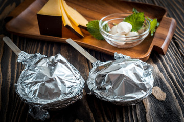 Hot meat baked in foil cooked in a coconut under the foil. On a wooden dark background