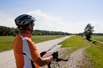 Biker reading map on rural road