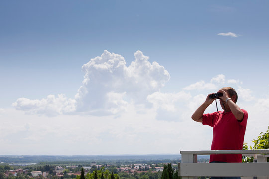 Older Man Using Binoculars On Roof