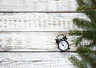 clock and spruce branches on a white wooden background