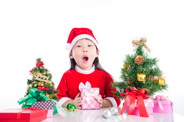 Little asian girl sitting with Christmas tree and gift boxes over white background