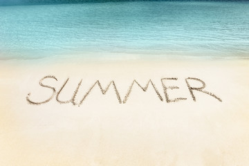 The Summer word written on the beach sand.