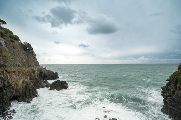 Fototapeta na wymiar Sea waves crashing on the rock. At Riomaggiore in La Spezia, One of the famous Cinque Terre, Italy