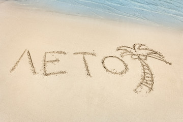 The Summer word written in Russian on the beach sand.