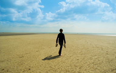 Girl carrying shoes on beach