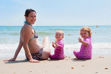 Mother sitting on beach with daughters