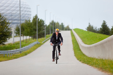 Obraz premium Businessman riding bicycle in urban park