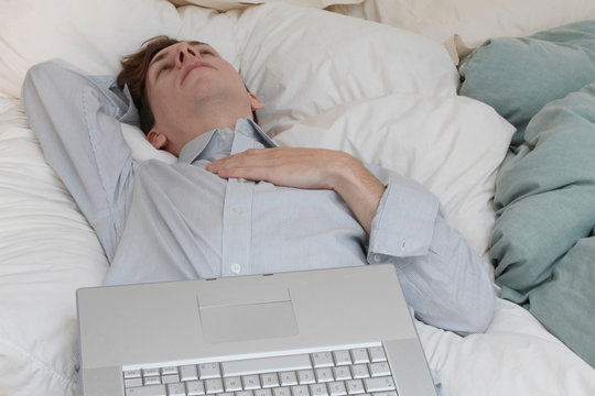 Businessman with laptop laying on bed