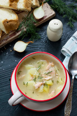 Finnish fish soup with red fish with spices and fresh dill on a dark stone background.