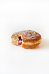 German fried donut, so called Krapfen, Berliner or Pfannkuchen, filled with rose hip jam and dusted with cinnamon sugar, traditionally eaten at carnival and at New Year's Eve on white background