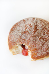 German fried donut, so called Krapfen, Berliner or Pfannkuchen, filled with rose hip jam and dusted with cinnamon sugar, traditionally eaten at carnival and at New Year's Eve on white background
