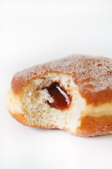 German fried donut, so called Krapfen, Berliner or Pfannkuchen, filled with rose hip jam and dusted with cinnamon sugar, traditionally eaten at carnival and at New Year's Eve on white background