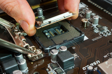 Fototapeta na wymiar Computer technician installing CPU into motherboard. Close up.