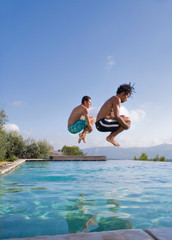 Young men jumping into a pool