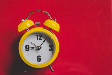 Retro yellow alarm clock with Nine Five Minutes Old Style, Top View on Red Backdrop