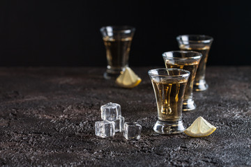 Strong whiskey in glasses with ice and sliced lemon on the dark background