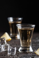 Strong whiskey in glasses with ice and sliced lemon on the dark background