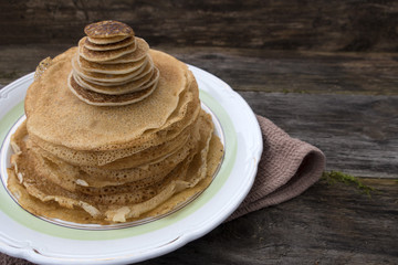 Large and small pancakes located on an old wooden table. Close-up and place for copy space.