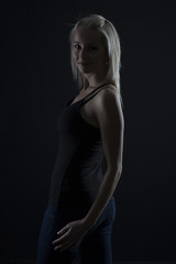 Beautiful blond woman in denim and black top in the dark with selective lighting