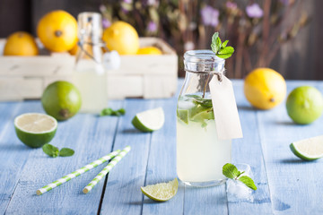 Lime and lemon lemonade with mint in the bottle with label on the blue background