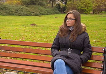 girl with long hair sitting on a park bench