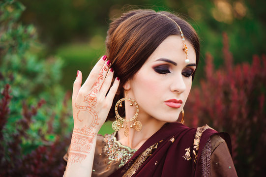 Portrait of beautiful indian girl. Young hindu woman model with tatoo mehndi and kundan jewelry. Traditional Indian costume saree.