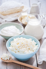 Obraz na płótnie Canvas Organic Farming Cottage cheese in a blue bowl, sour cream, butter, cheese and milk