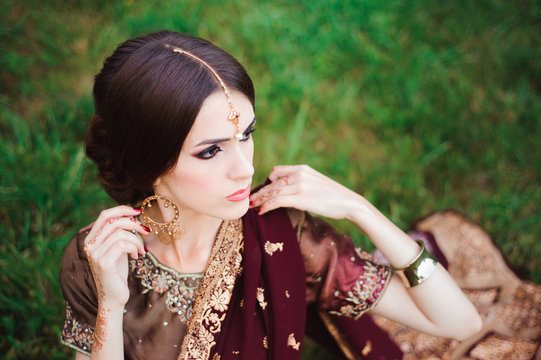Indian girl with oriental jewellery and make-up henna applied to hand. Brunette Hindu model girl with Indian jewels.