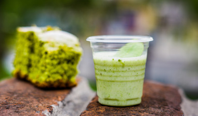 Close up of a coca yogurt served in a plastic glass with a mint leaf inside and a delicious blurred...