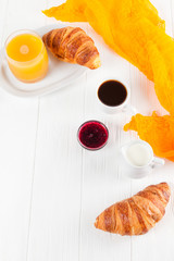 Freshly baked croissant orange juice, jam, cup of black coffee on white wooden background. French breakfast. Fresh pastries for morning. Delicious dessert. Closeup photography. Vertical banner