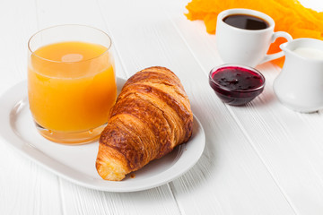 Freshly baked croissant orange juice, jam, cup of black coffee on white wooden background. French breakfast. Fresh pastries for morning. Delicious dessert. Closeup photography. Horizontal banner
