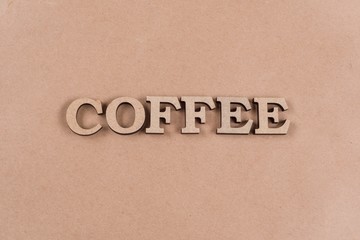 Word coffee with abstract wooden letters. Background old kraft paper, copy space