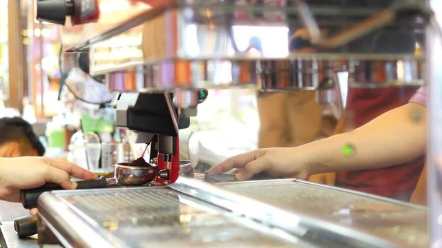 Barista is making coffee using grinder machine in a coffee shop