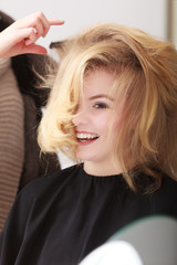Fototapeta premium Hairstylist combing female client blond girl in hairdressing salon