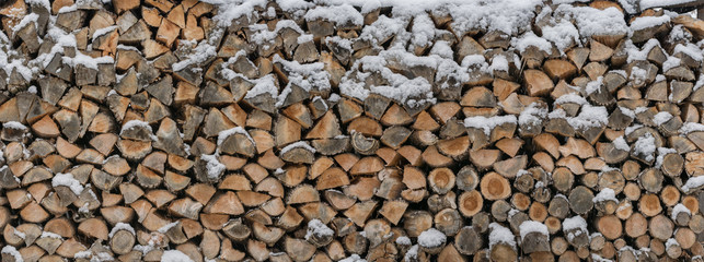 Firewood is stored in the snow as a wooden texture