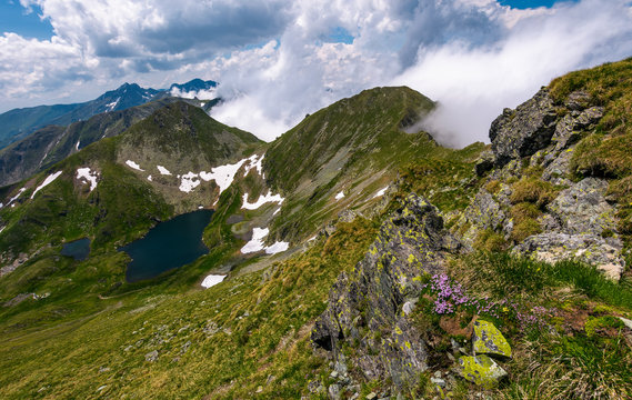 edge of steep slope on rocky hillside in cloudy weather. dramatic scenery with snow near glacier in Fagaras mountains