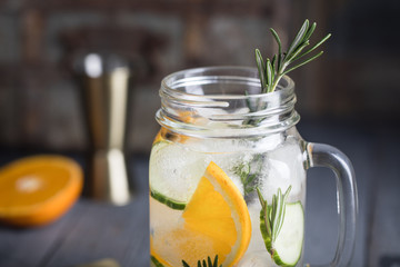 Homemade orange margarita with cucumber and rosemary on the dark rustic background for the party